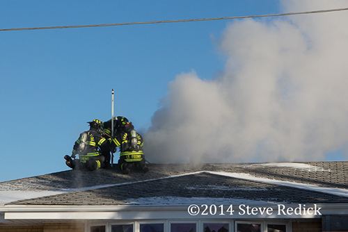 firemen ventilate roof at house fire