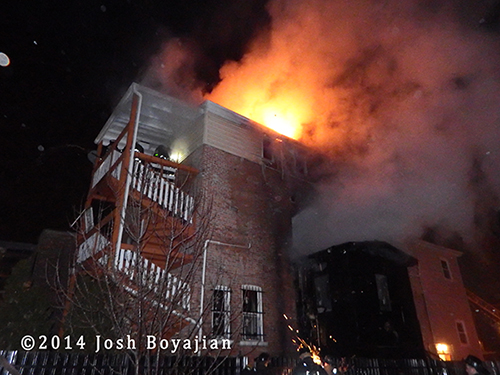 flames shoot from the roof of a building at night