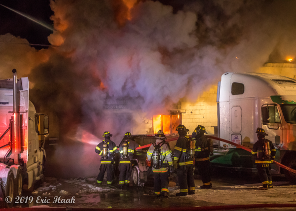 Firefighters battle fire in a truck repair shop