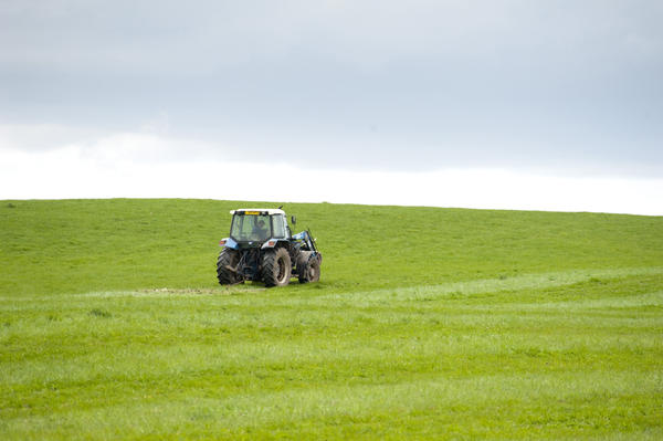 stock image Farmer working with his tractor on a lush green pasture in the English countryside to ensure the best possible grazing for his livestock