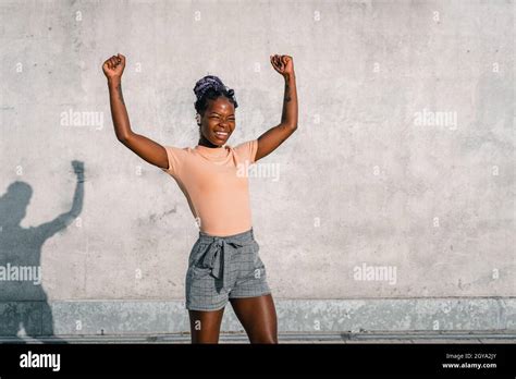 black girl raises her arms in victory sign Stock Photo - Alamy