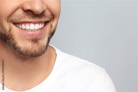 Young man with beautiful smile on grey background. Teeth whitening Stock Photo | Adobe Stock