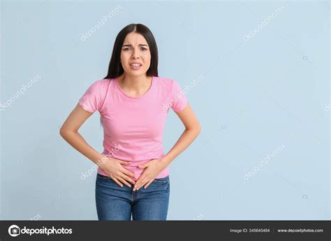 Young woman suffering from menstrual cramps on color background Stock Photo by ©serezniy 345645484