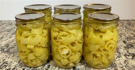 four jars filled with pickles sitting on top of a counter