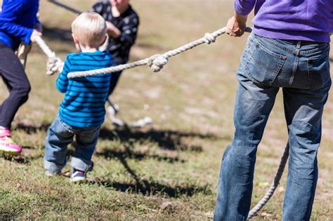 Premium Photo | Two families playing vintage rope pulling game in the park.