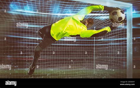 Soccer goalkeeper, in fluorescent uniform, makes a save and avoids a goal during a night match ...