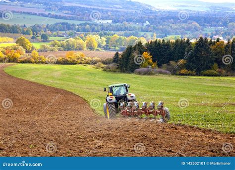 Tractor Plowing Field With Silos In Background Stock Photography | CartoonDealer.com #152695880