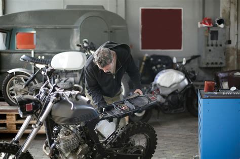 Anonymous adult male mechanic fixing motorbike in garage · Free Stock Photo