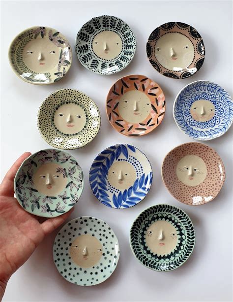 a hand is holding a small bowl with many designs on it and there are nine bowls in the shape of ...