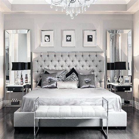 a bedroom with a bed, mirror and chandelier in black and white colors