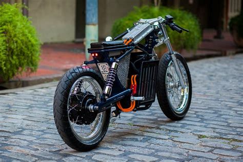 a black motorcycle parked on top of a cobblestone road