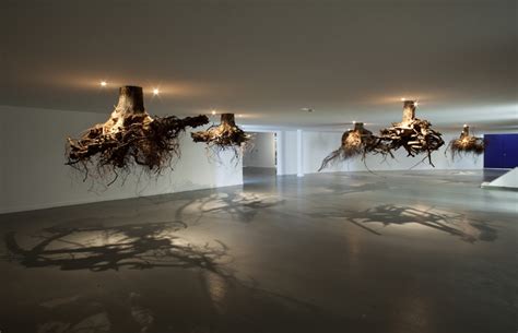 tree roots emerge from the ceiling in an installation by giuseppe licari