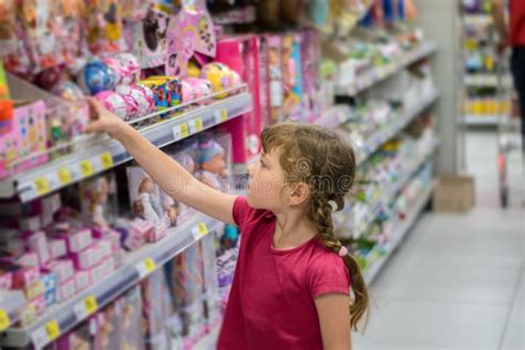 A Little Girl is Buying Presents. the Child Chooses Toys in the ...