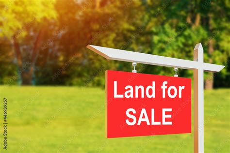 Land for sale sign. Red sign for sale plot. Green lawn behind sign ...