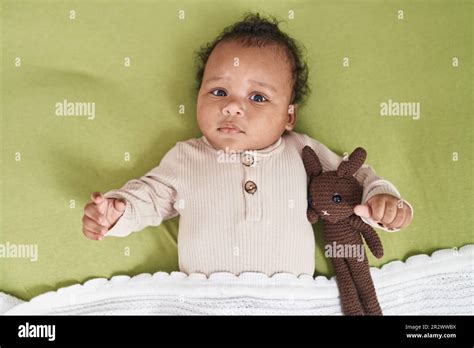 African american baby relaxing on bed with doll at bedroom Stock Photo - Alamy