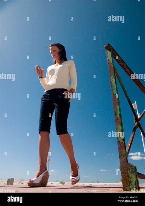 a low angle shot of young woman walking towards camera checking her ...