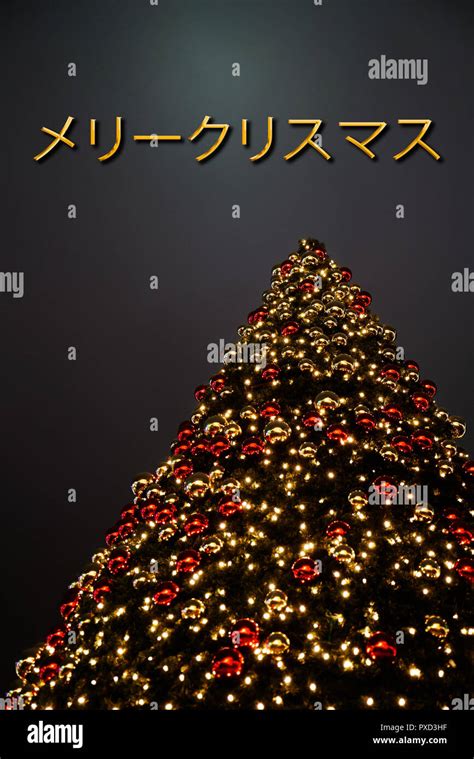 A Christmas tree with golden and red decoration. The Japanese text „メリークリスマス“ means "Merry ...