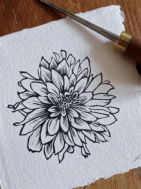 a black and white drawing of a flower on a piece of paper next to a pair of scissors