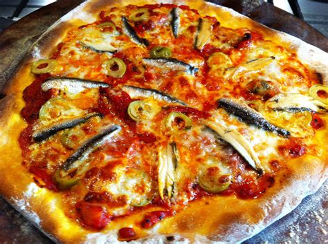 A homemade pizza, lots of anchovy and some green olives...