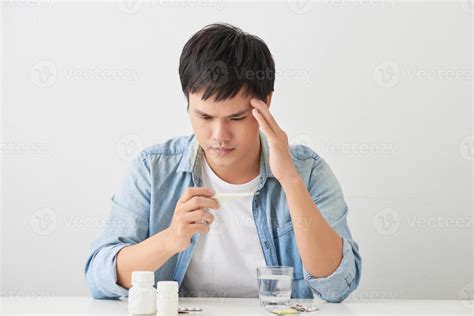 Sick young man looks at a thermometer 12745431 Stock Photo at Vecteezy