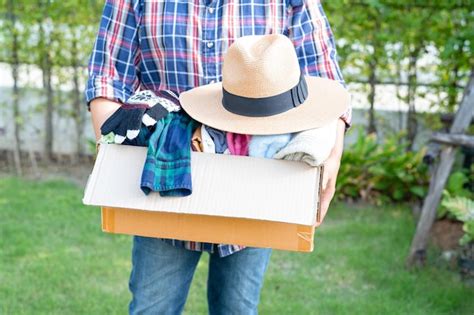 Premium Photo | Volunteer woman provide clothing donation box with used clothes to support help ...