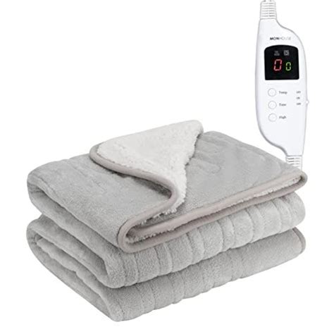 an electric heated blanket with two blankets stacked next to it and thermometer on top