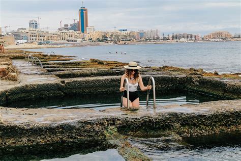 a woman is standing in the water with her hat on and wearing a bathing suit