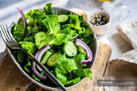 Healthy green salad concept with iceberg salad leaves, cucumber, sesame oil and seeds served in ...