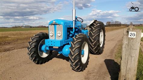 a blue tractor parked on the side of a dirt road