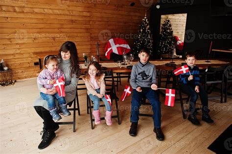 Family with Denmark flags inside wooden house sitting by table. Travel to Scandinavian countries ...