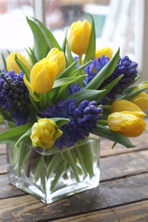 a glass vase filled with yellow and purple flowers