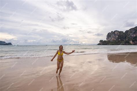 Premium Photo | Woman wearing yellow bikini smiling and running on railay beach at sunset thailand