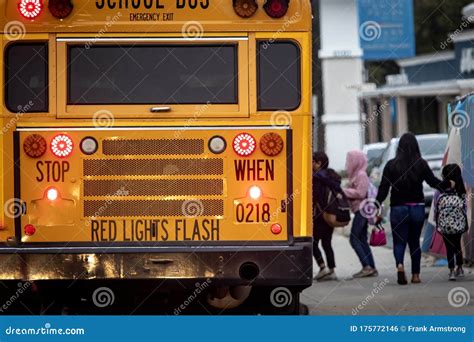 School Bus with Flashing Lights and Children Boarding Diffused in the ...