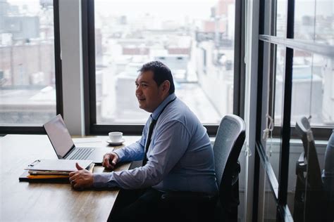 Positive ethnic male entrepreneur working on laptop in office center · Free Stock Photo