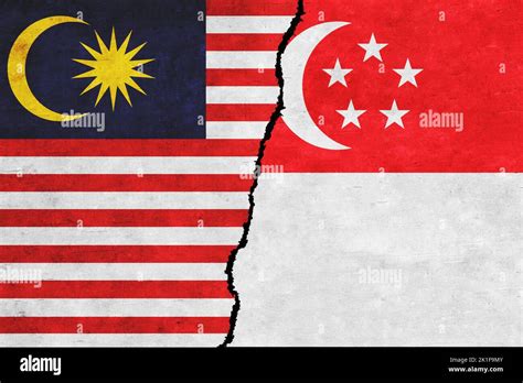 Singapore and Malaysia painted flags on a wall with a crack. Singapore and Malaysia conflict ...