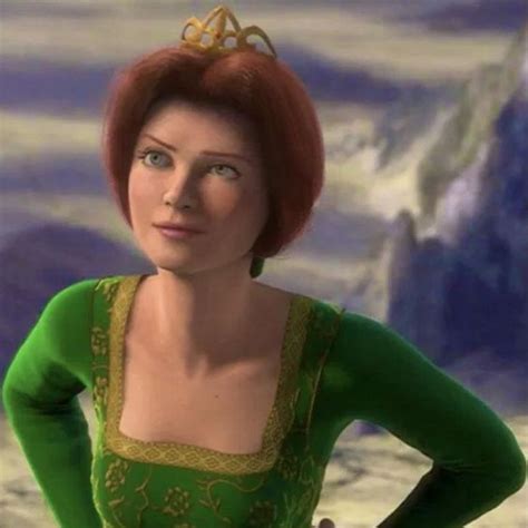 a woman with red hair wearing a green dress and gold tiara, standing in front of a painting