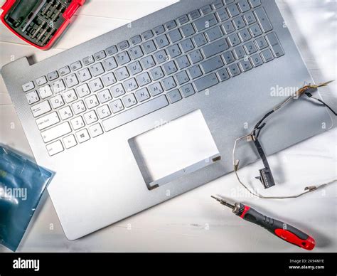 Repair and maintenance of computer laptop, laptop lid disassembled, and screwdriver hanging ...