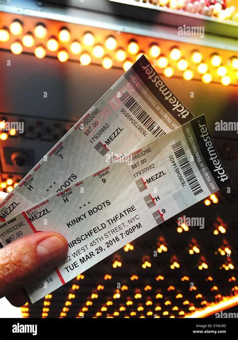 Man holding two Broadway show tickets for Kinky Boots in front of marquee lights, Times square ...