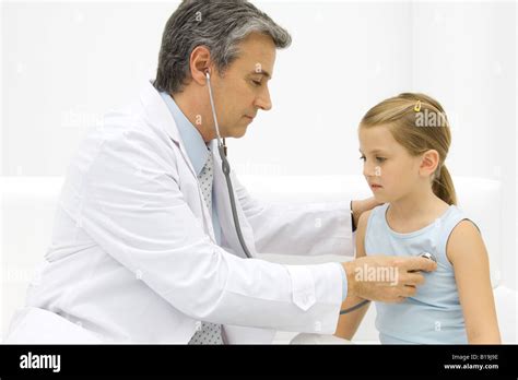 Doctor listening to little girl's heart with stethoscope, side view ...