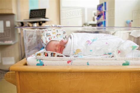 Newborn baby boy sleeping in crib at hospital - Stock Photo - Dissolve