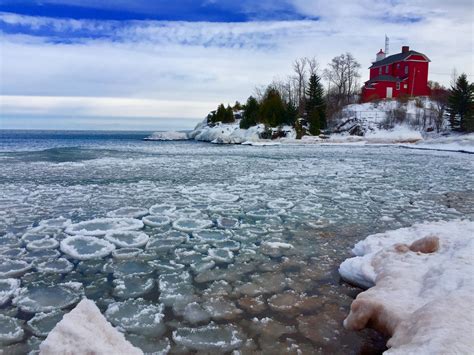 the water is crystal clear and there are ice floes in front of an old red building