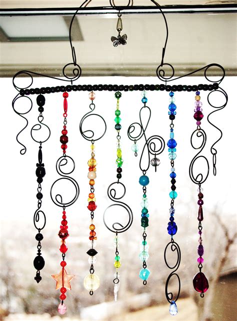 a wind chime hanging from the side of a window with beads and stars on it