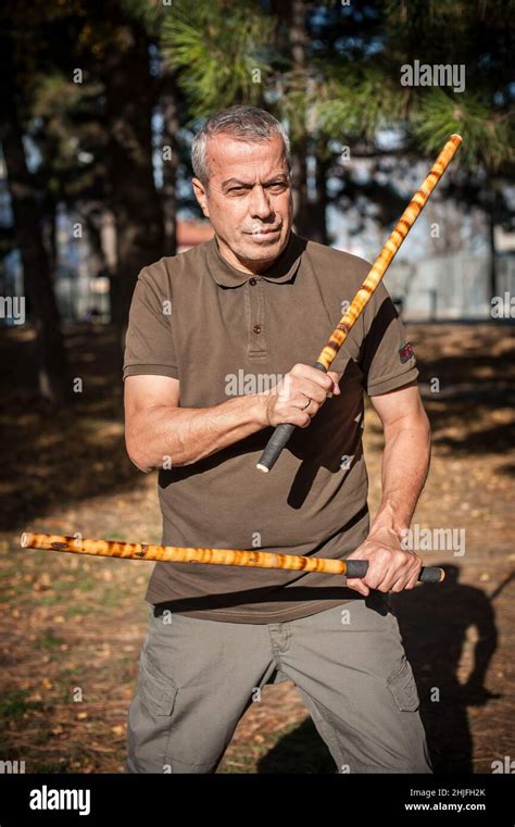 Escrima and kapap instructor demonstrates sticks fighting techniques in public park. Filipino ...