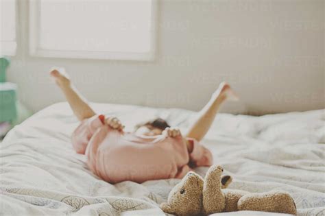 Playful girl lying on bed at home stock photo