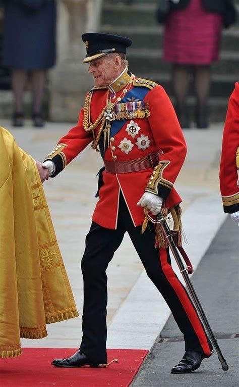 an older man in uniform walking on a red carpet next to another man with a cane