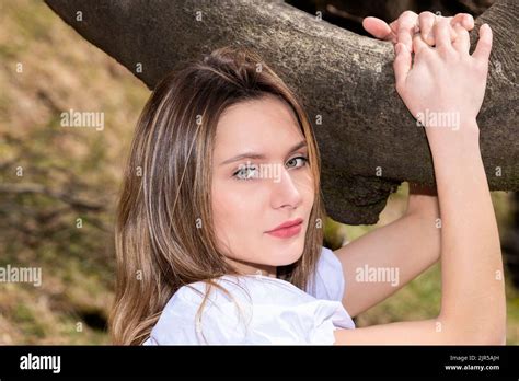 pretty blonde woman hugging a tree branch in a white dress Stock Photo - Alamy