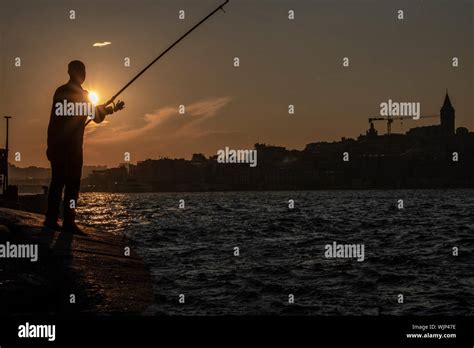 Sunset silhouette of holding fish Stock Photo - Alamy