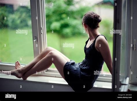 Young woman sitting on a window sill Stock Photo - Alamy