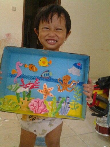 a little boy holding up a box with an image of fish and sea animals on it