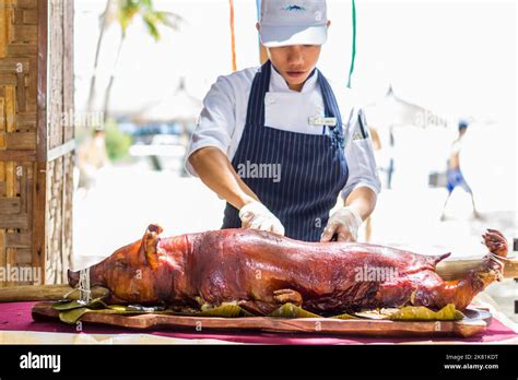 A restaurant staff slices a portion of a whole Filipino lechon or roast pig in Cebu, Philippines ...